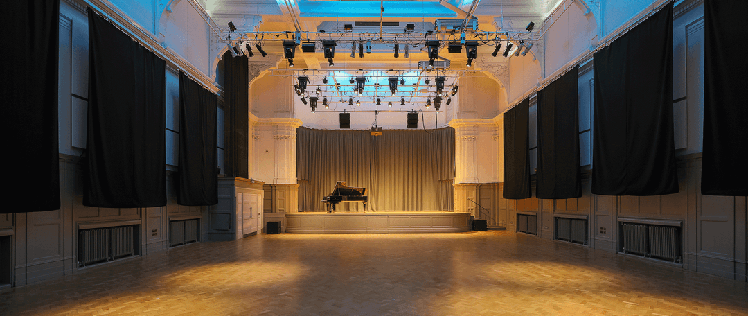 Bishopsgate Great Hall showing a piano on stage with overhead stage lighting