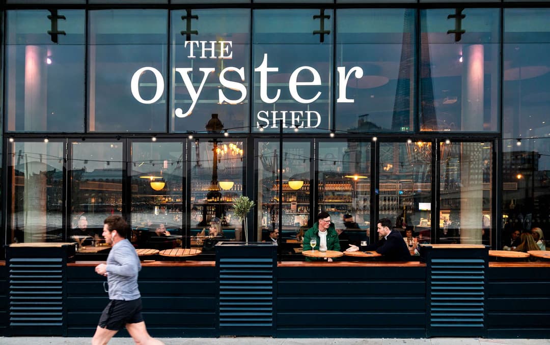 Exterior view of The Oyster Shed pub with people enjoying drinks on the patio outside